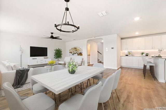 dining room with arched walkways, recessed lighting, visible vents, light wood-style floors, and stairs