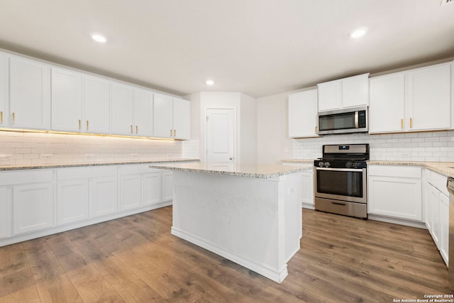 kitchen featuring white cabinetry, appliances with stainless steel finishes, backsplash, and wood finished floors