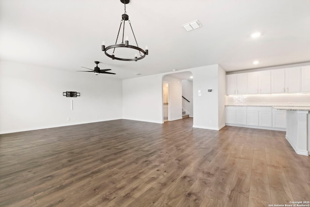 unfurnished living room with visible vents, arched walkways, a ceiling fan, wood finished floors, and recessed lighting