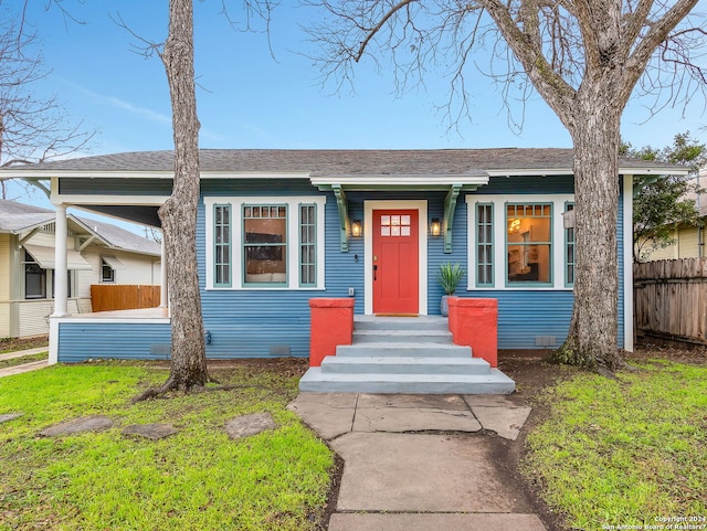 view of front of home featuring roof with shingles, crawl space, a front yard, and fence