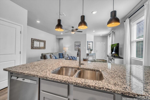 kitchen with pendant lighting, visible vents, stainless steel dishwasher, open floor plan, and a sink