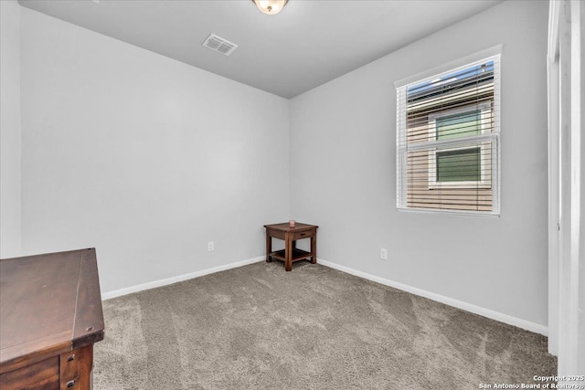 unfurnished room with carpet floors, visible vents, and baseboards