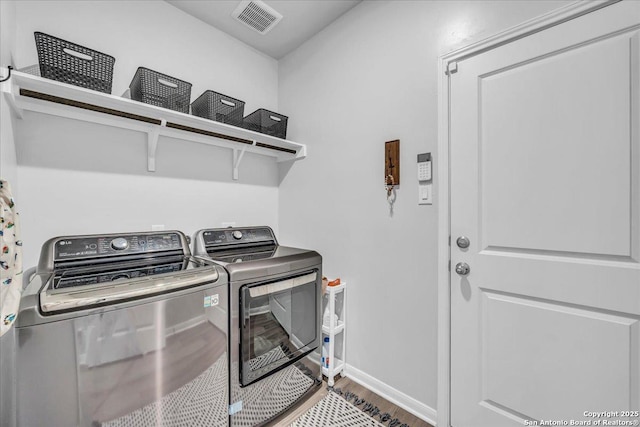 clothes washing area with laundry area, baseboards, visible vents, wood finished floors, and separate washer and dryer