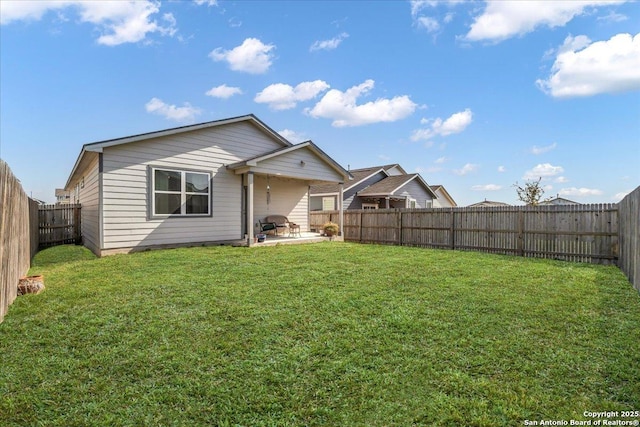 rear view of house with a fenced backyard, a yard, and a patio