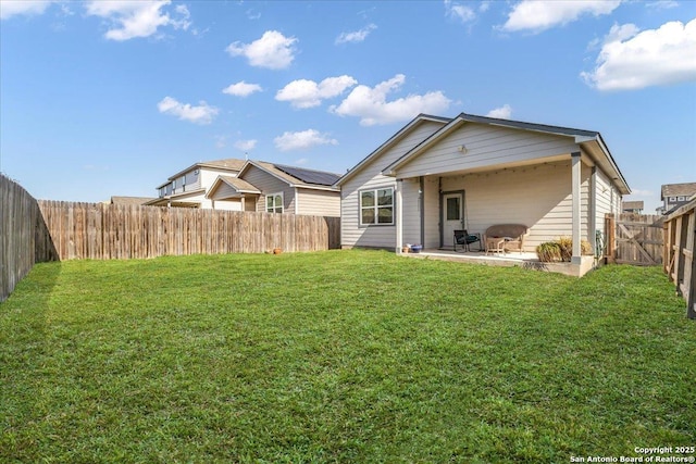 rear view of house featuring a patio area, a yard, and a fenced backyard