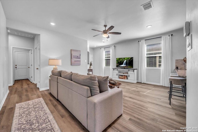 living room featuring ceiling fan, wood finished floors, visible vents, and recessed lighting