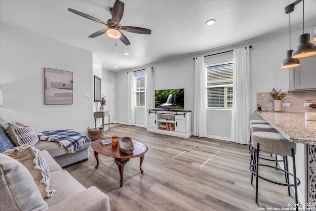 living area with a ceiling fan, light wood-type flooring, baseboards, and recessed lighting