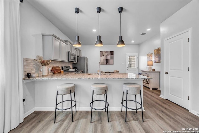 kitchen featuring stainless steel appliances, visible vents, gray cabinetry, a sink, and a peninsula