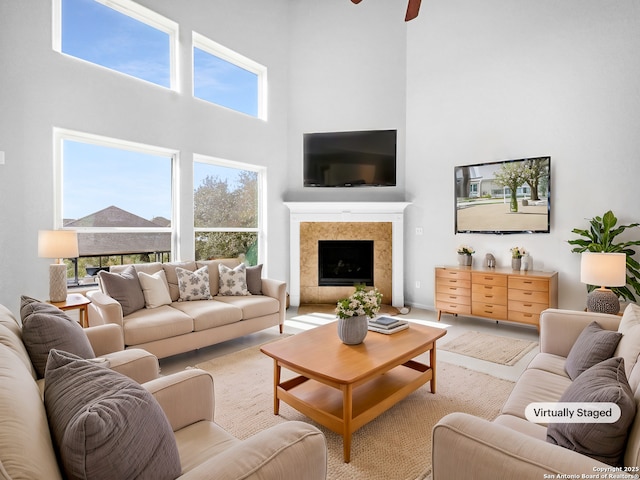 living room featuring a healthy amount of sunlight, a fireplace, and a towering ceiling