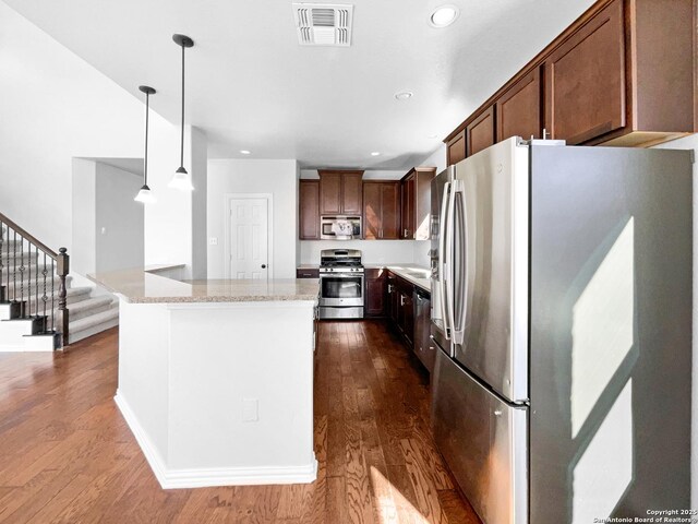 12518 Ponder, San Antonio, TX 78245 - kitchen with light stone counters, visible vents, dark wood-style flooring, stainless steel appliances, and pendant lighting