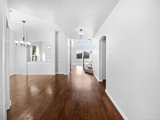 12518 Ponder, San Antonio, TX 78245 - unfurnished living room with baseboards, stairs, arched walkways, an inviting chandelier, and dark wood-style floors