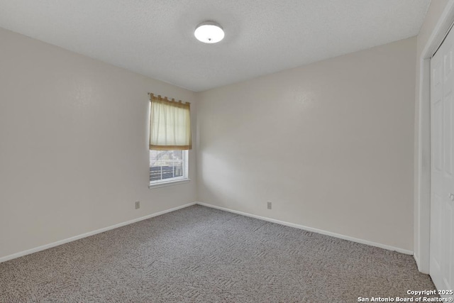 unfurnished room featuring carpet, a textured ceiling, and baseboards