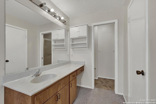 bathroom with baseboards, a textured ceiling, and vanity