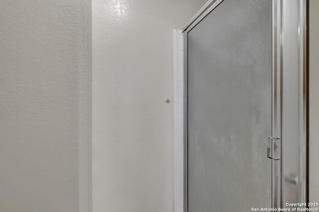 full bathroom with a textured wall and a shower stall