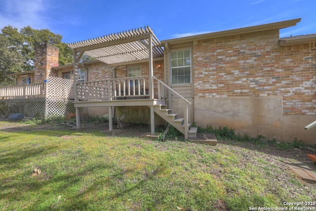 back of property with brick siding, a yard, a wooden deck, and a pergola