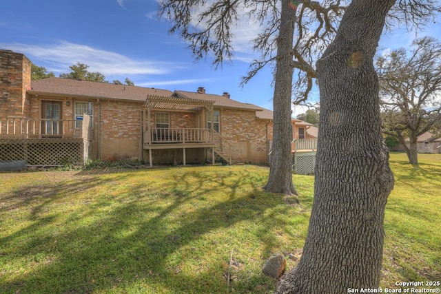 rear view of property with brick siding, a yard, and a deck