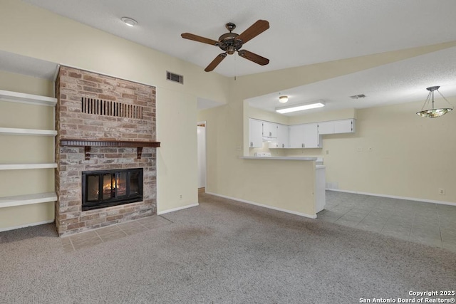 unfurnished living room with a brick fireplace, carpet, visible vents, and a textured ceiling