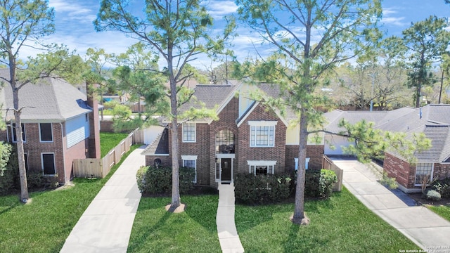 traditional-style house featuring brick siding, a front yard, and fence