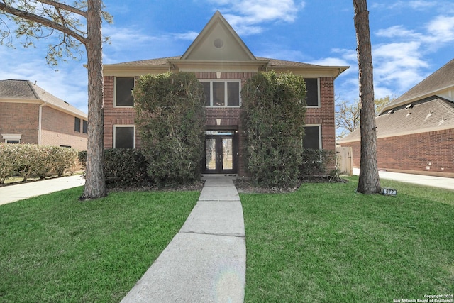 view of front of house featuring french doors, brick siding, and a front yard