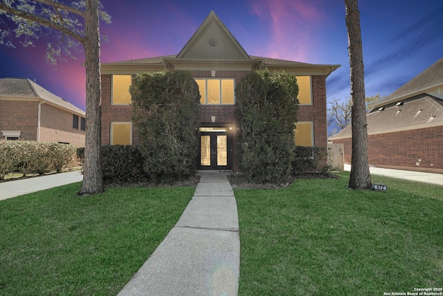 traditional-style house with brick siding and a front lawn