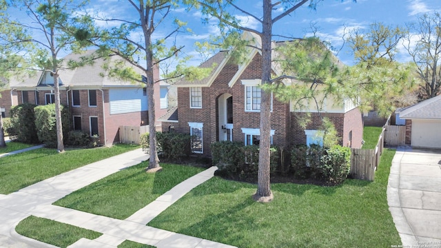 view of front facade featuring a front yard, fence, and brick siding