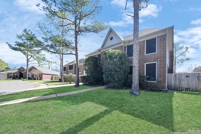 view of front of property featuring brick siding, a front yard, and fence