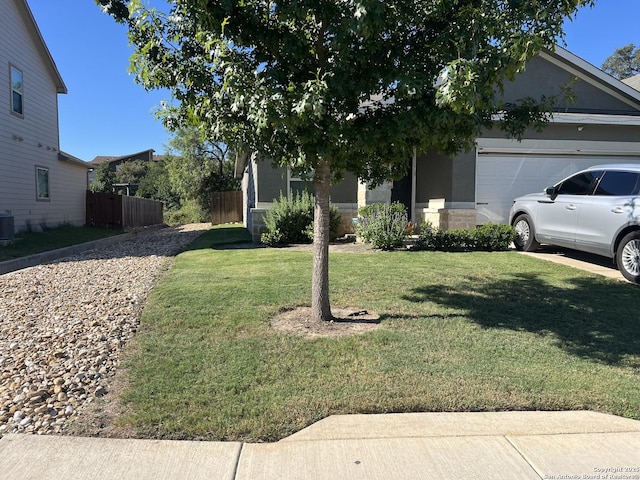 view of front of home with an attached garage, fence, a front lawn, and central AC