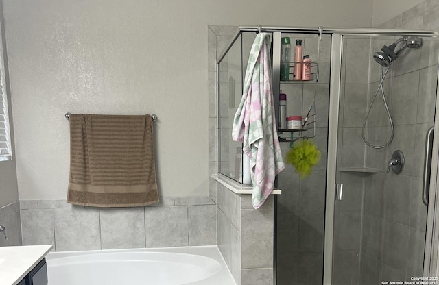 bathroom with a shower stall, vanity, and a bath