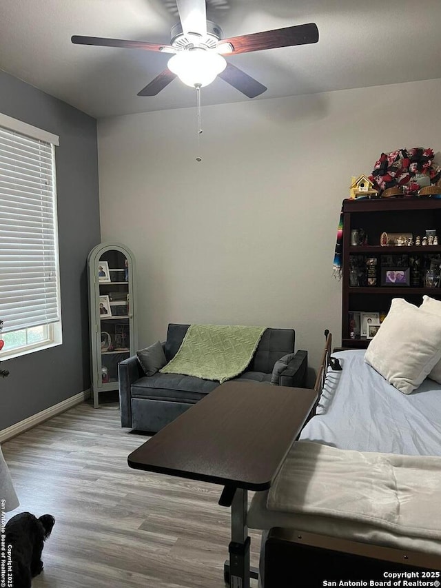 bedroom featuring a ceiling fan, baseboards, and wood finished floors