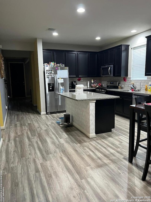 kitchen featuring light wood finished floors, appliances with stainless steel finishes, visible vents, and a center island