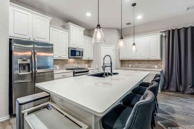 kitchen featuring appliances with stainless steel finishes, white cabinets, a sink, and wood finished floors