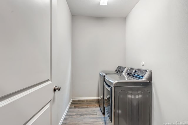 clothes washing area featuring laundry area, washer and clothes dryer, wood finished floors, and baseboards