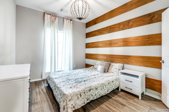 bedroom with baseboards, visible vents, and wood finished floors