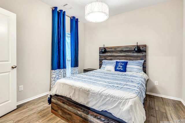 bedroom with visible vents, baseboards, and wood finished floors