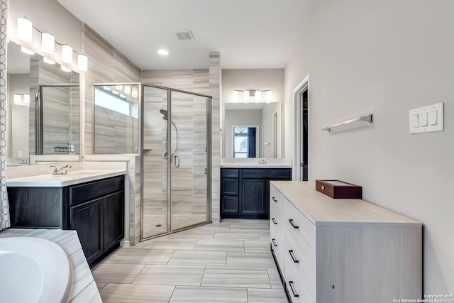 full bath featuring a sink, a shower stall, visible vents, and two vanities