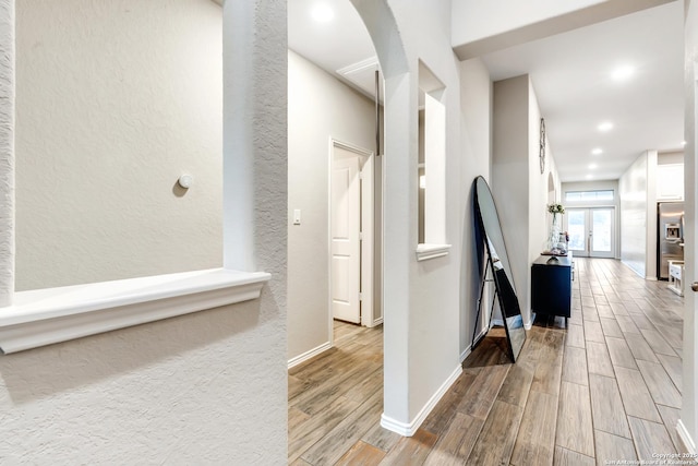 hallway featuring baseboards, recessed lighting, arched walkways, and wood tiled floor