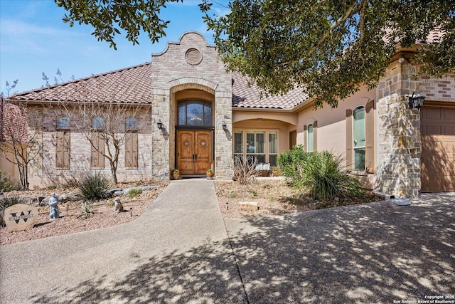 view of front of home with stone siding, a tiled roof, and stucco siding