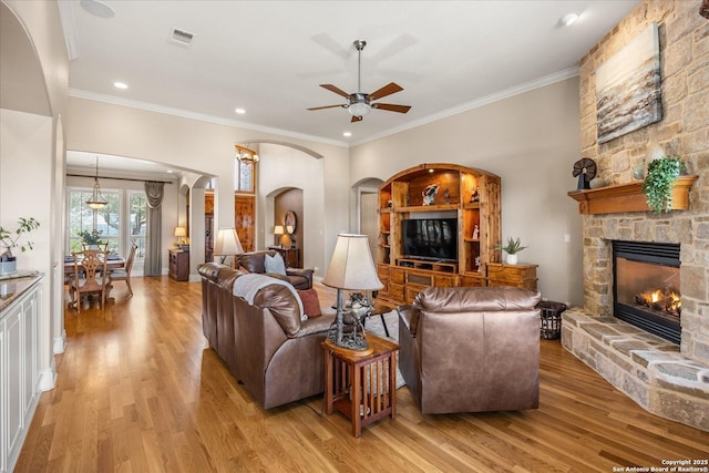 living area with light wood finished floors, a fireplace, and crown molding