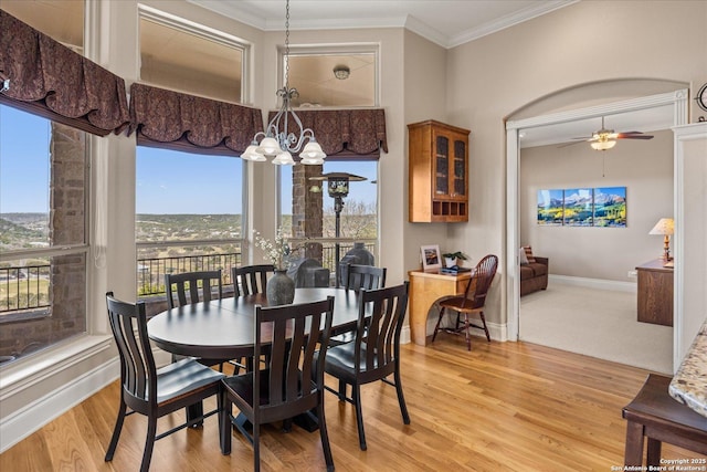 dining space with light wood-style floors, crown molding, baseboards, and ceiling fan with notable chandelier