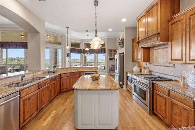 kitchen with light wood-style flooring, stainless steel appliances, a sink, backsplash, and a center island