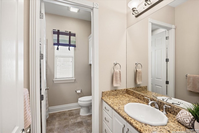 bathroom featuring baseboards, vanity, and toilet