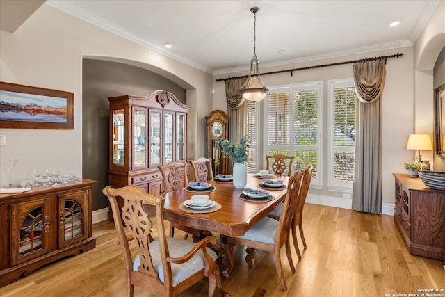 dining space featuring light wood-style floors, crown molding, and baseboards