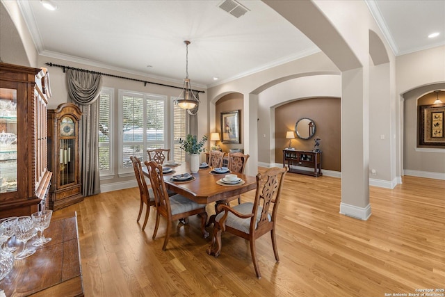 dining room with baseboards, crown molding, visible vents, and light wood-style floors