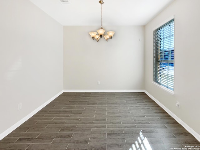 spare room with dark wood-style floors, baseboards, and an inviting chandelier