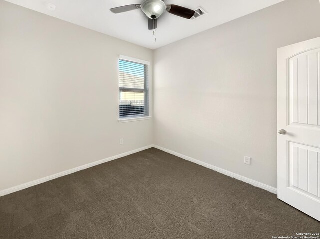 spare room featuring dark colored carpet, visible vents, ceiling fan, and baseboards