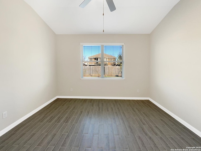 empty room featuring dark wood-type flooring, a ceiling fan, and baseboards