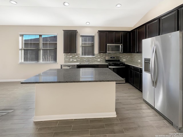 kitchen with decorative backsplash, dark stone countertops, a center island, stainless steel appliances, and recessed lighting