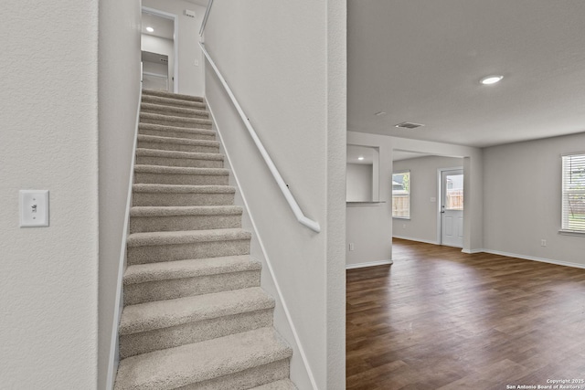 stairway with recessed lighting, visible vents, baseboards, and wood finished floors