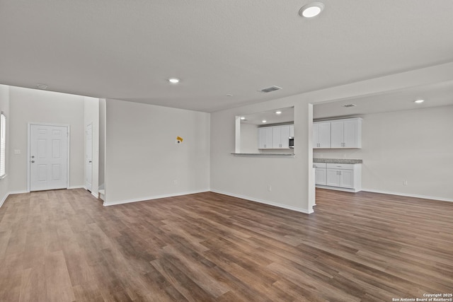 unfurnished living room with recessed lighting, visible vents, baseboards, and wood finished floors