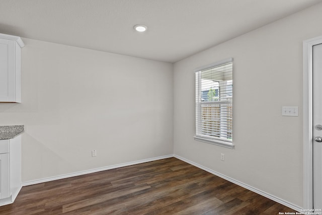 unfurnished room featuring dark wood-type flooring and baseboards